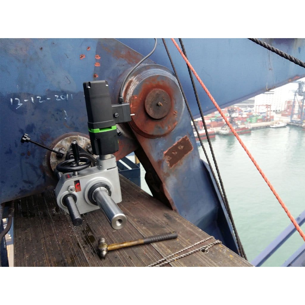 Photograph capturing a Portable Line Borer positioned on an on-ship crane. The image depicts the equipment securely fastened to the crane, showcasing its adaptability for on-board machining operations in maritime settings. Various components and connections are visible, highlighting the functionality of the device in a marine environment.