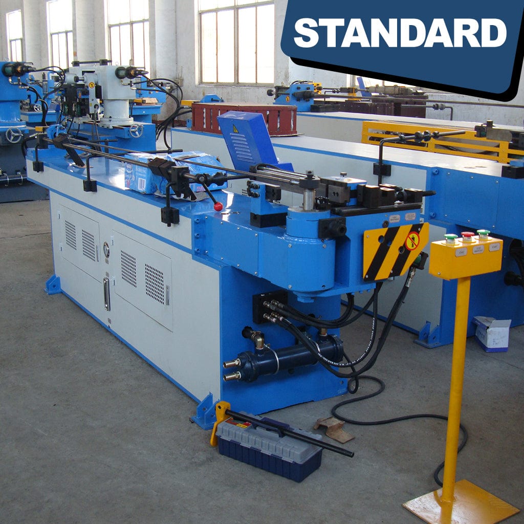 The STANDARD BTNC-38, 1-axis Hydraulic Mandrel Tube Bender, displays a series of switches and controls arranged on its panel. The switches and levers are positioned alongside a digital interface, enabling precise adjustment and control of the bending process. The machine&#39;s mechanical components and bending mechanism are visible in the background, showcasing the industrial setup for tube bending.